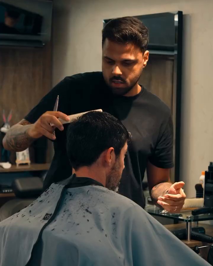 Átila cortando cabelo com tesoura e pente, cliente de costas
