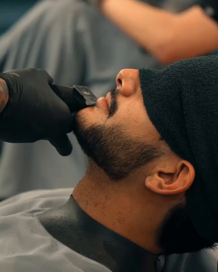 Acabamento de barba com máquina, cliente com toalha sobre os olhos
